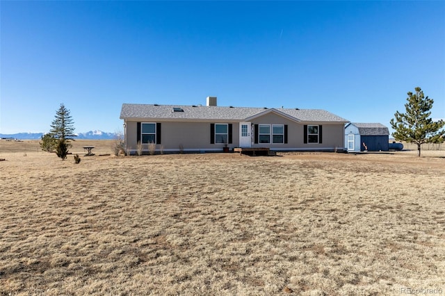 rear view of property with a mountain view and a storage shed