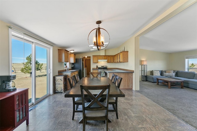 dining room featuring sink, carpet, a chandelier, and vaulted ceiling