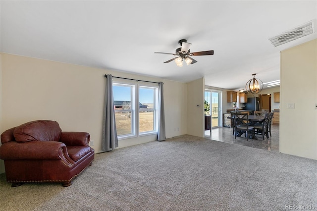 sitting room with carpet and ceiling fan with notable chandelier