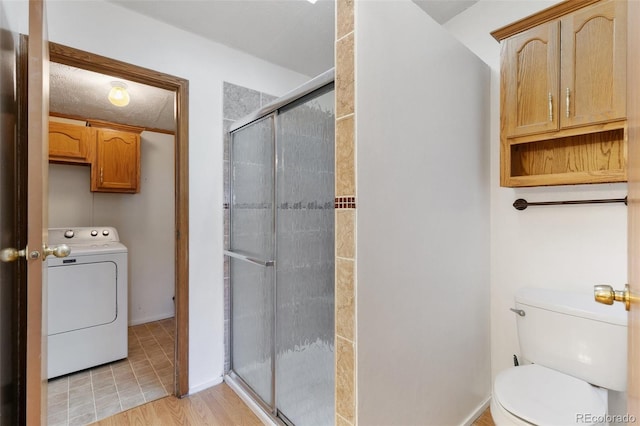 bathroom featuring wood-type flooring, washer / clothes dryer, toilet, and an enclosed shower