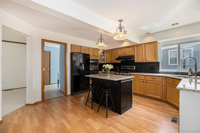 9346 Lark Sparrow Dr, Highlands Ranch, CO 80126 - kitchen with appliances with stainless steel finishes, a sink, under cabinet range hood, a kitchen breakfast bar, and light wood-style floors
