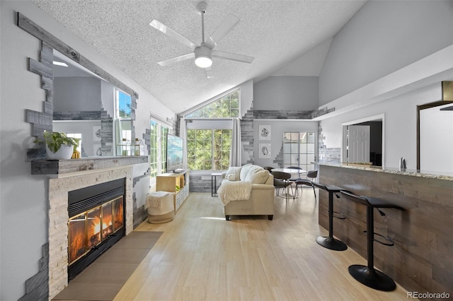 13824 E Lehigh Ave Unit B, Aurora, CO 80014 - living area featuring a textured ceiling, wood finished floors, high vaulted ceiling, a ceiling fan, and a fireplace with flush hearth