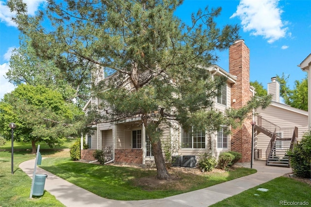 13824 E Lehigh Ave Unit B, Aurora, CO 80014 - obstructed view of property with brick siding, a front yard, a chimney, and stairs