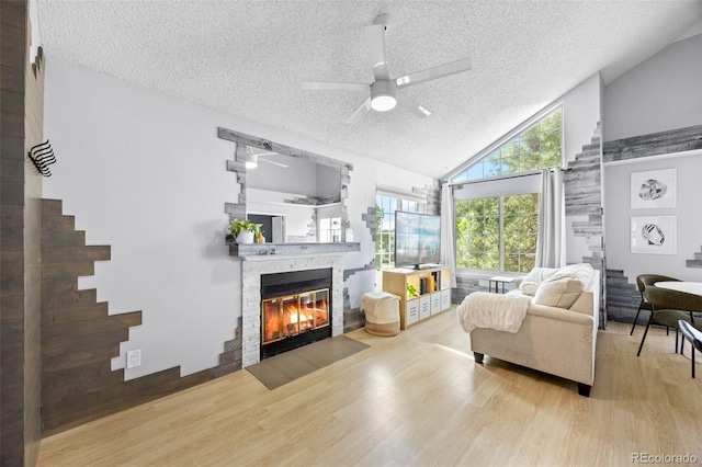 13824 E Lehigh Ave Unit B, Aurora, CO 80014 - living room featuring a textured ceiling, wood finished floors, a fireplace with flush hearth, ceiling fan, and high vaulted ceiling