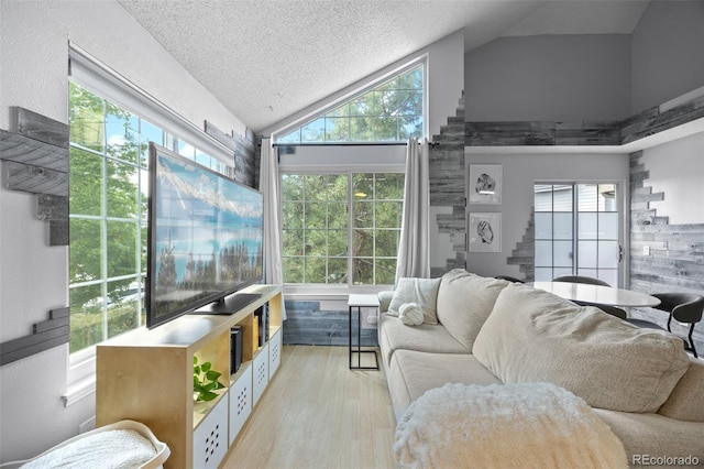 13824 E Lehigh Ave Unit B, Aurora, CO 80014 - living area featuring light wood-type flooring, healthy amount of natural light, a textured ceiling, and high vaulted ceiling