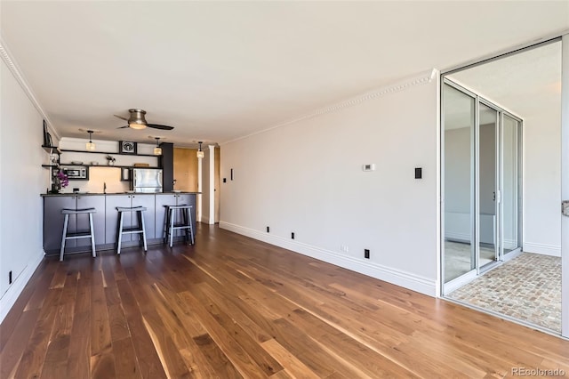 1050 N Corona St Unit 308, Denver, CO 80218 - unfurnished living room featuring hardwood / wood-style floors, bar area, a ceiling fan, baseboards, and ornamental molding