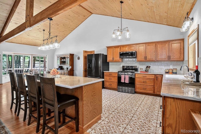 1539 Bluebird Dr, Bailey, CO 80421 - kitchen featuring stainless steel appliances, a wooden ceiling with exposed beams, a chandelier, brown cabinetry, and hanging light fixtures