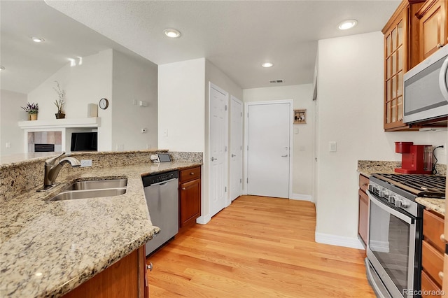 kitchen with stainless steel appliances, a sink, visible vents, light wood-style floors, and brown cabinets