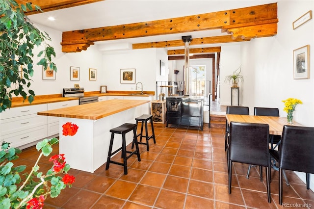11 Baca Mdws, Moffat, CO 81131 - kitchen with wood counters, stainless steel electric stove, beamed ceiling, a kitchen bar, and white cabinets