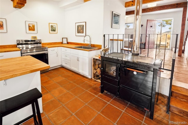 11 Baca Mdws, Moffat, CO 81131 - kitchen featuring butcher block counters, stainless steel electric range, dark tile patterned flooring, and white cabinetry