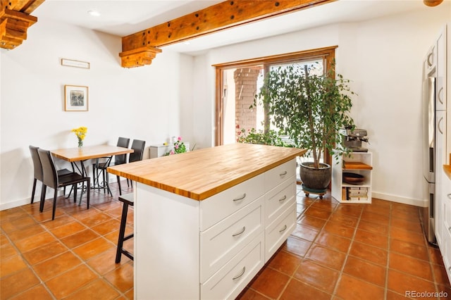 11 Baca Mdws, Moffat, CO 81131 - kitchen with wood counters, beam ceiling, a kitchen breakfast bar, white cabinetry, and dark tile patterned floors
