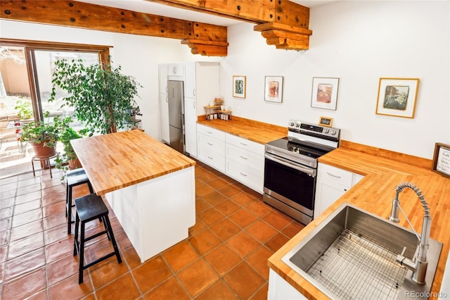 11 Baca Mdws, Moffat, CO 81131 - kitchen featuring wooden counters, appliances with stainless steel finishes, white cabinetry, a breakfast bar area, and beam ceiling
