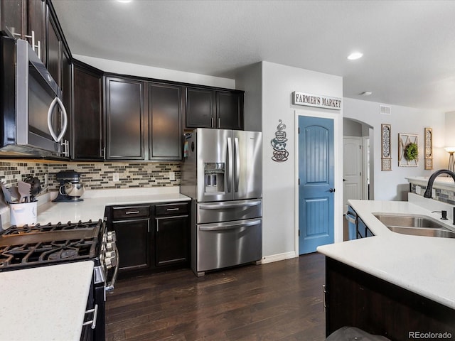 6832 Sequoia St, Frederick, CO 80530 - kitchen with appliances with stainless steel finishes, arched walkways, light countertops, backsplash, and dark wood-style flooring