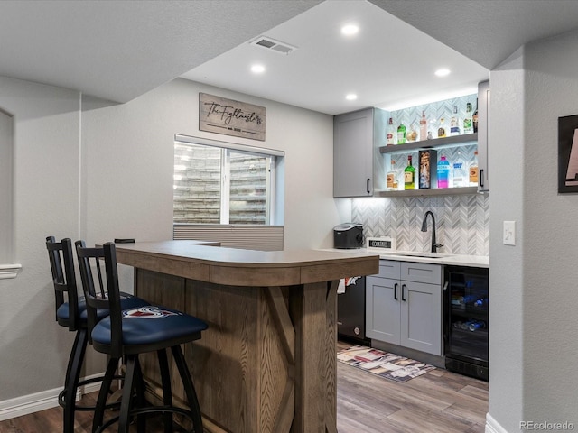 6832 Sequoia St, Frederick, CO 80530 - indoor wet bar featuring wine cooler, light wood-style flooring, decorative backsplash, and recessed lighting