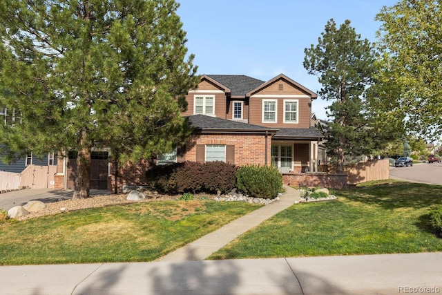 view of front of property featuring fence, brick siding, a front yard, concrete driveway, and covered porch