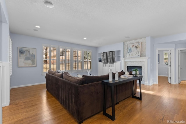 living room featuring baseboards, a large fireplace, and wood finished floors