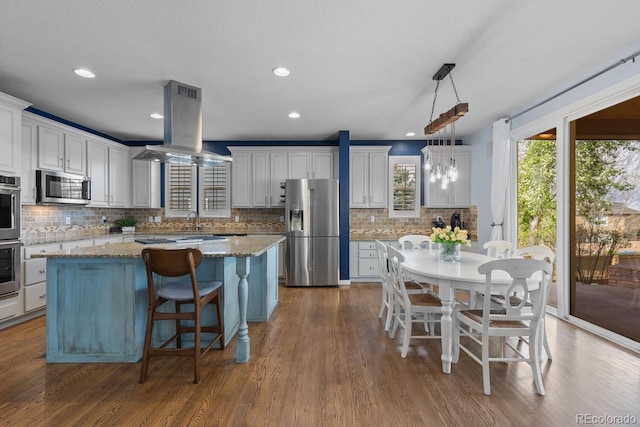 kitchen featuring a kitchen island, backsplash, stainless steel appliances, and island exhaust hood