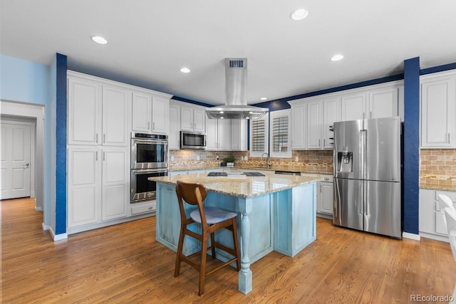 kitchen with a kitchen island, white cabinets, tasteful backsplash, island exhaust hood, and stainless steel appliances