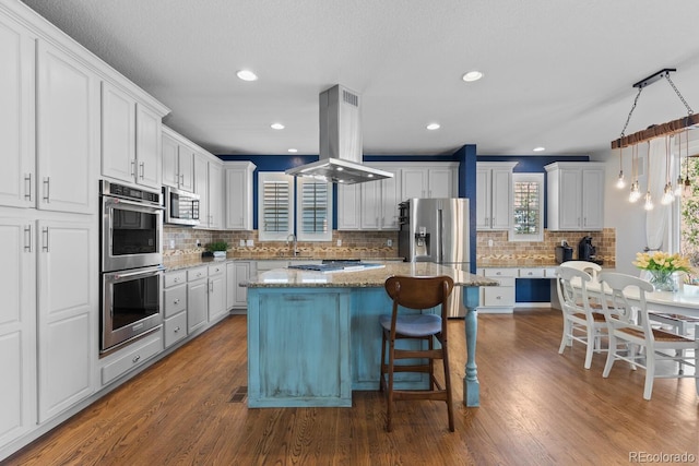 kitchen with appliances with stainless steel finishes, tasteful backsplash, island exhaust hood, and dark wood-type flooring