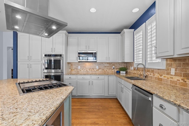kitchen with white cabinets, extractor fan, appliances with stainless steel finishes, and a sink