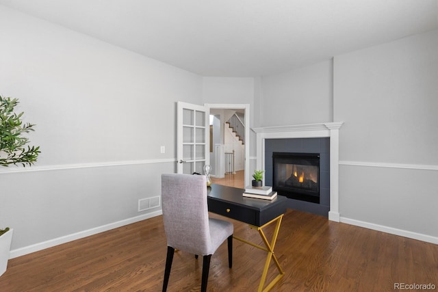 office space with visible vents, baseboards, wood finished floors, and a tile fireplace