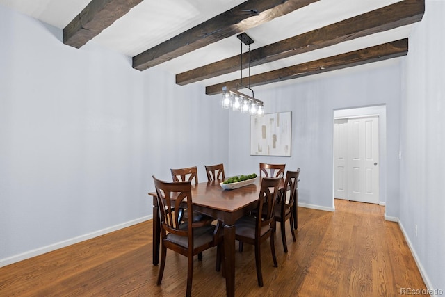 dining room featuring baseboards, wood finished floors, and beamed ceiling