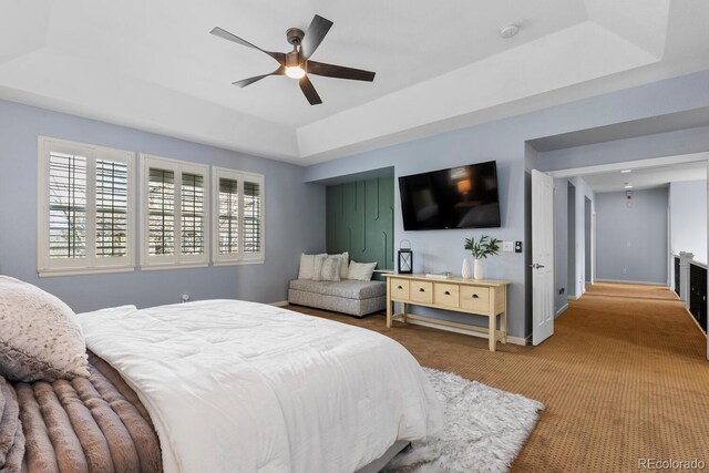 carpeted bedroom featuring baseboards, a ceiling fan, and a tray ceiling