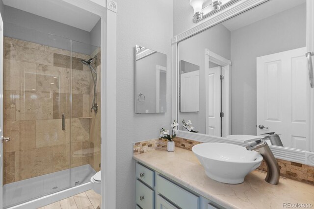 bathroom with vanity, toilet, and a stall shower