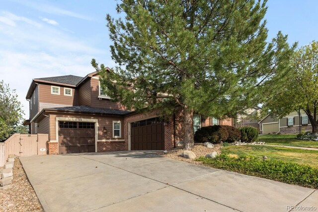 view of front of house featuring concrete driveway, brick siding, a gate, and a garage