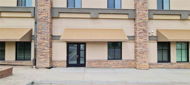 entrance to property featuring stucco siding, stone siding, and a standing seam roof