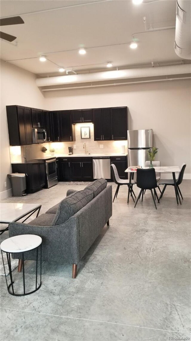 living area featuring concrete flooring, recessed lighting, and baseboards