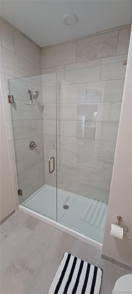 bathroom with a shower stall and tile patterned flooring
