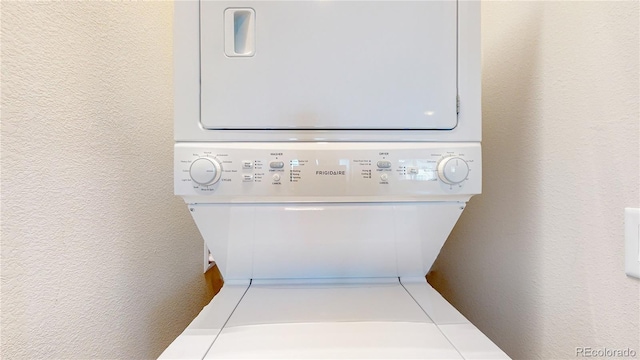 laundry area with estacked washer and dryer and a textured wall
