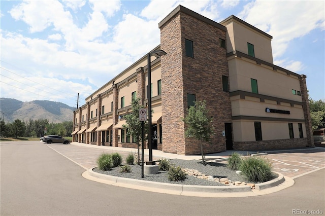 view of building exterior featuring a mountain view and uncovered parking