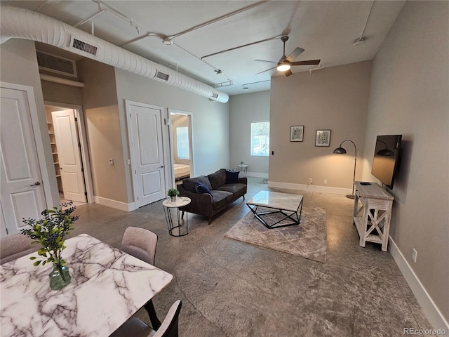 living area with a ceiling fan and baseboards