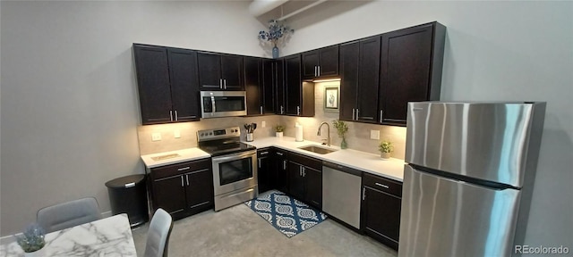 kitchen featuring stainless steel appliances, a sink, decorative backsplash, and concrete flooring