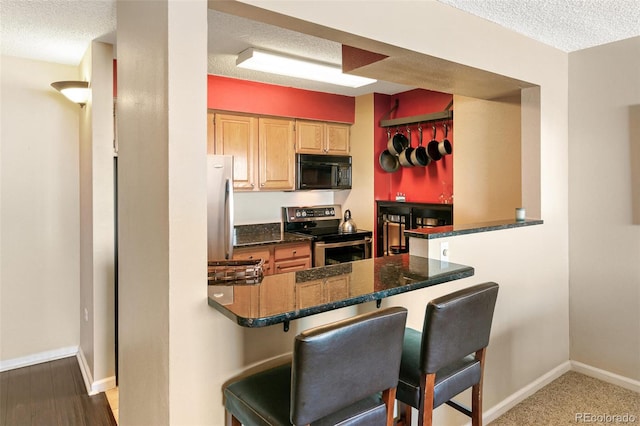 1020 15th St Unit 16A, Denver, CO 80202 - kitchen featuring appliances with stainless steel finishes, a textured ceiling, a kitchen breakfast bar, baseboards, and a peninsula