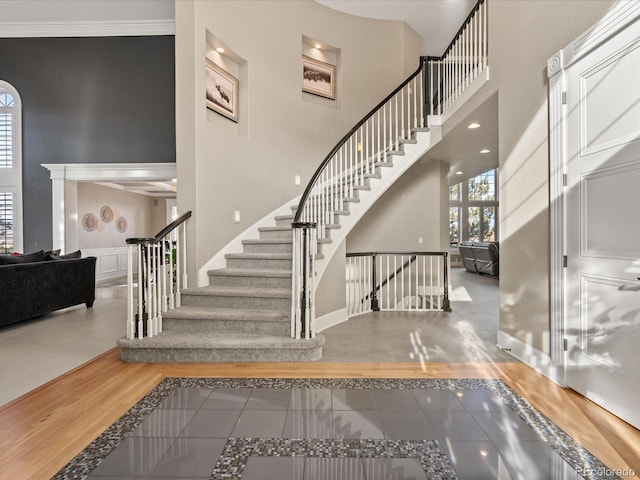 staircase with tile patterned flooring, a towering ceiling, and ornamental molding