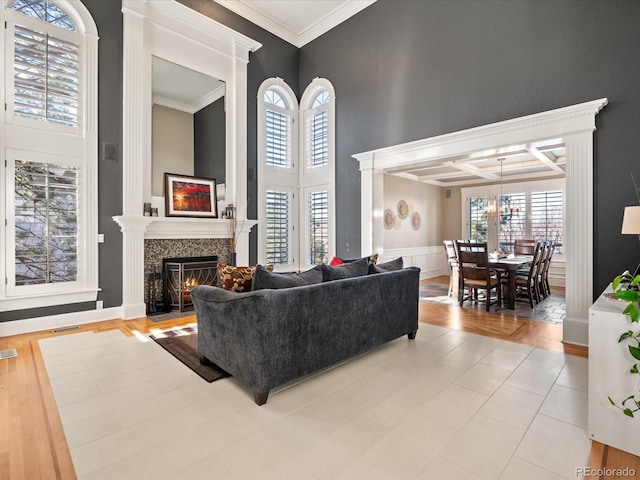 living room featuring beam ceiling, a premium fireplace, ornamental molding, and coffered ceiling