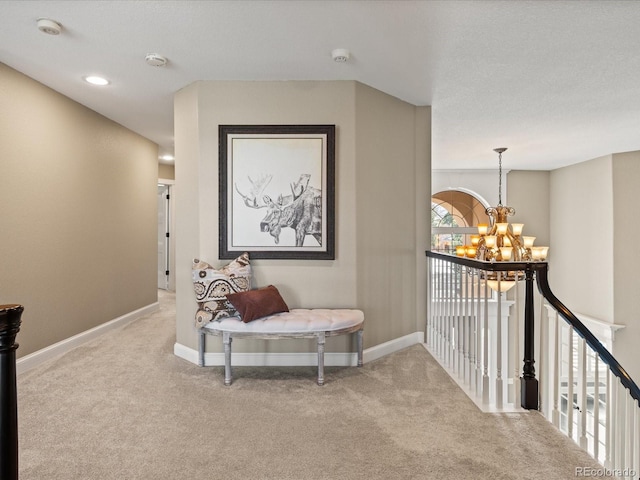 hall featuring light colored carpet and an inviting chandelier