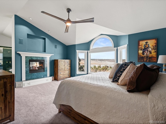 bedroom with a tiled fireplace, ceiling fan, carpet, and lofted ceiling