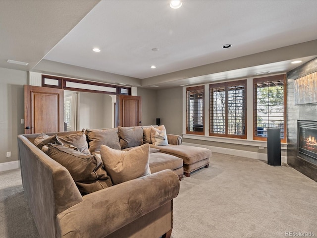 home theater with a tile fireplace and light colored carpet