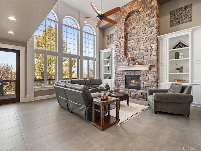 living room with light tile patterned floors, a fireplace, a high ceiling, and a ceiling fan