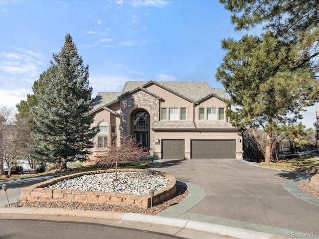 view of front of home featuring an attached garage, stone siding, concrete driveway, and stucco siding