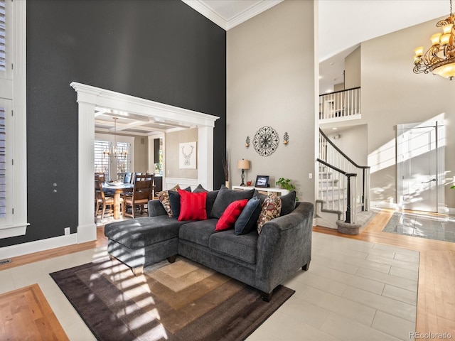 living room with a chandelier, ornamental molding, a high ceiling, and stairs