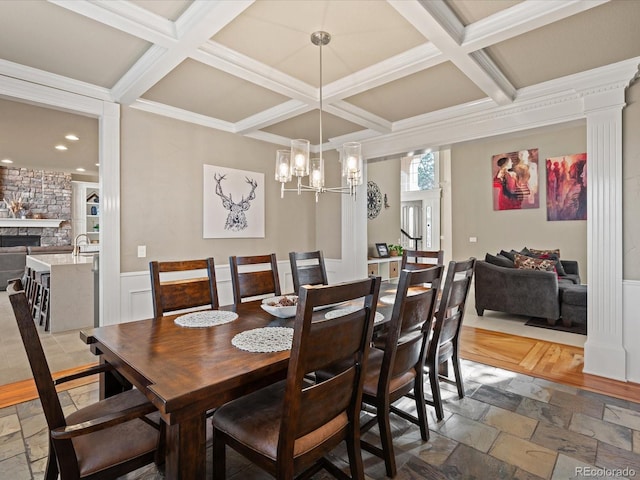 dining room featuring a fireplace, beam ceiling, coffered ceiling, and stone tile flooring