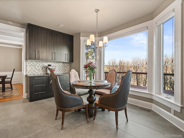 dining area featuring baseboards, light tile patterned floors, visible vents, and a notable chandelier