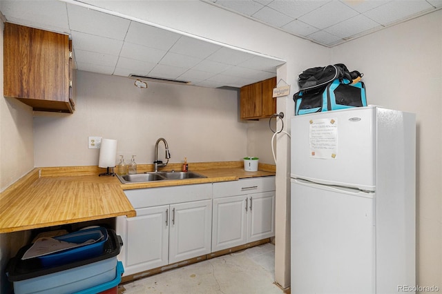 6898 S Franklin Cir, Centennial, CO 80122 - kitchen with freestanding refrigerator, light countertops, concrete flooring, a paneled ceiling, and white cabinets