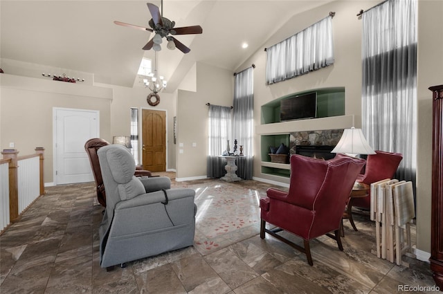 living room with ceiling fan with notable chandelier, high vaulted ceiling, radiator, and a stone fireplace