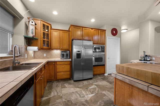 kitchen featuring backsplash, tile countertops, sink, and stainless steel appliances